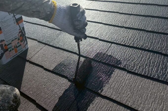 千葉市若葉区S様邸のスレート屋根にローラーで中塗り塗装（主材1回目）を施工している様子。屋根材の凹凸に塗料を丁寧に浸透させている工程。