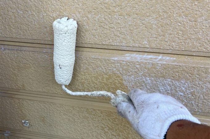 賃貸アパート外壁に下塗り塗装を行っている様子。外壁材へ塗料を浸透させる重要工程